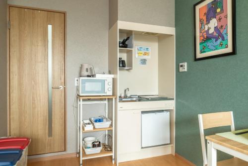 a small kitchen with a microwave on a shelf at 梅田まで電車で5分 1フロア貸切 駅徒歩3分 2024年フルリフォーム 建物3階 in Osaka