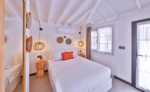 a white bedroom with a bed and a window at Caliza Alaçatı in Alaçatı