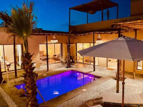 a house with a swimming pool with an umbrella at Superbe Villa piscine chauffée bali Marrakech in Marrakech