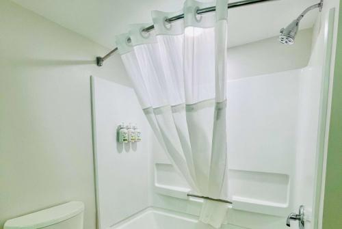 - un rideau de douche blanc dans la salle de bains pourvue de toilettes dans l'établissement Wingate by Wyndham Matthews, NC, à Matthews