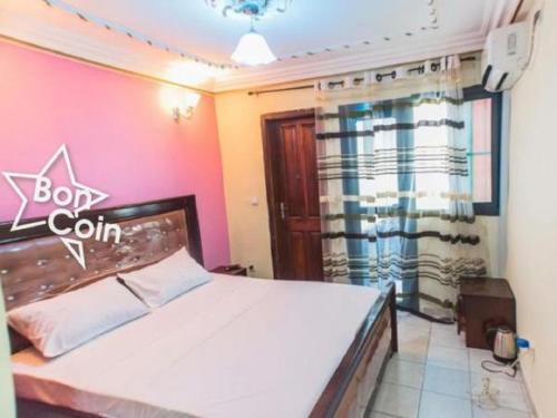 ein Schlafzimmer mit einem Bett mit einem Schild an der Wand in der Unterkunft Appartement meublé à Douala, Bonamoussadi in Douala