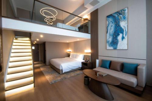 a hotel room with a bed and a couch and a staircase at Wyndham Dalian Jinpu in Dalian