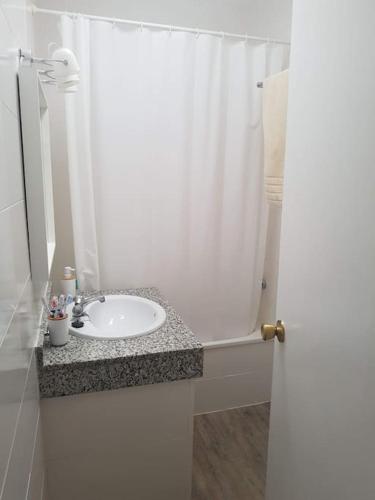 a bathroom with a sink and a white shower curtain at Casa en Punta Del Moral in Isla del Moral