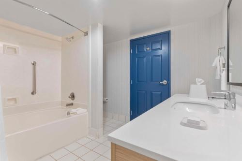 a bathroom with a sink and a blue door at Spark By Hilton Greensboro in Greensboro