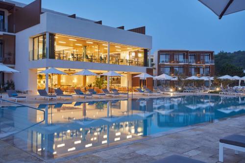 プエルト・デ・サン・ミゲルにあるThe Club Cala San Miguel Hotel Ibiza, Curio Collection by Hilton, Adults onlyのスイミングプール(椅子、パラソル付)