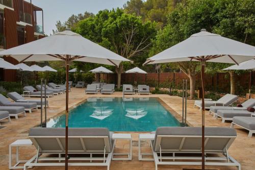 basen z leżakami i parasolami w obiekcie The Club Cala San Miguel Hotel Ibiza, Curio Collection by Hilton, Adults only w mieście Puerto de San Miguel