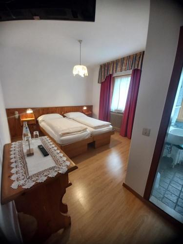 ein Schlafzimmer mit einem Bett und einem Tisch in einem Zimmer in der Unterkunft Hotel Dolomiti Saone in Tione di Trento