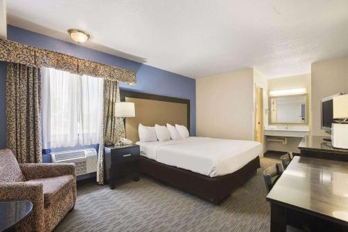 a large hotel room with a bed and a chair at Days Inn by Wyndham Mackinaw City - Bridgeview Area in Mackinaw City