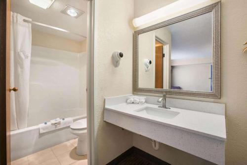 a bathroom with a sink and a toilet and a mirror at Days Inn by Wyndham Mackinaw City - Bridgeview Area in Mackinaw City