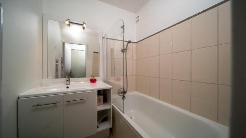 une salle de bain avec un lavabo, une baignoire et un miroir dans l'établissement LES TERRASSES DE LA FOUX -291 - Studio 4 pers, à La Foux