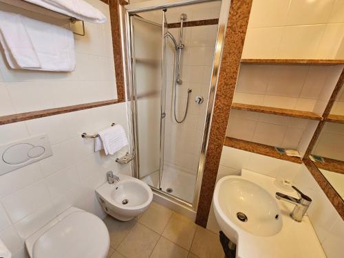a bathroom with a shower and a toilet and a sink at Hotel Fiorella in Senigallia