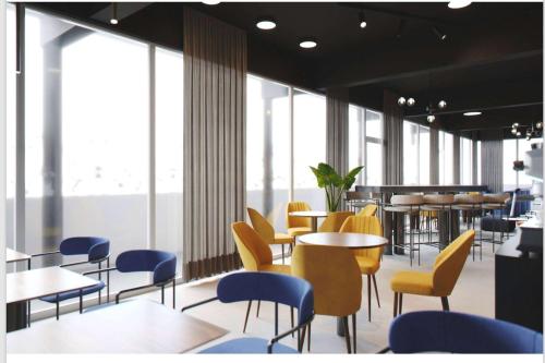 a restaurant with yellow chairs and tables and windows at Aspire Palais Recklinghausen, Trademark Collection by Wyndham in Recklinghausen