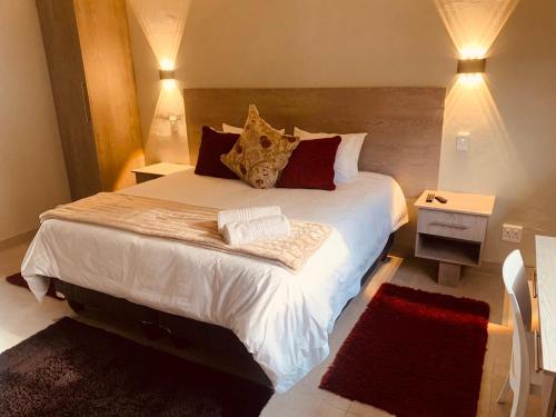 um quarto com uma cama grande com lençóis brancos e almofadas em Conti-INN Guesthouse em Queenstown
