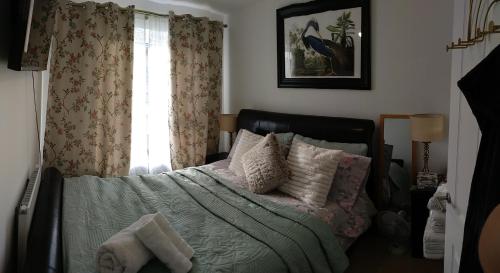 ein Schlafzimmer mit einem Bett mit Kissen und einem Fenster in der Unterkunft House Rose 1 in Prescot