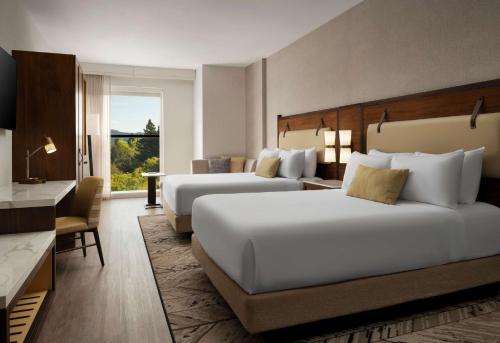a hotel room with two beds and a desk at Hotel Centro Sonoma Wine Country, Tapestry Collection Hilton in Rohnert Park
