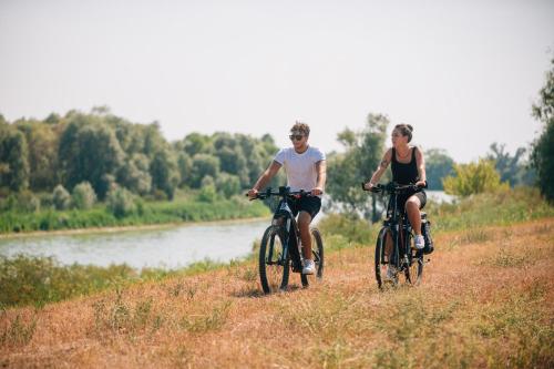 un hombre y una mujer montando bicicletas en una colina junto a un río en Hotel Ponte Molo en Porto Tolle
