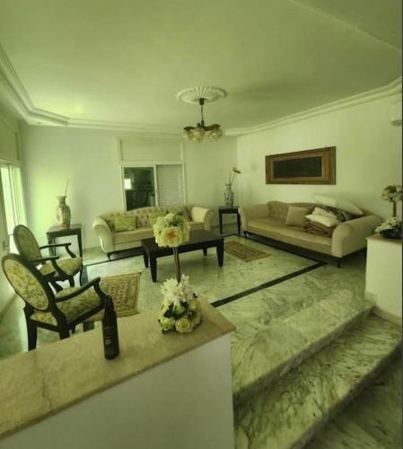 ein Wohnzimmer mit einem Sofa und einem Tisch in der Unterkunft Villa à yasmine hammamet in Nabeul