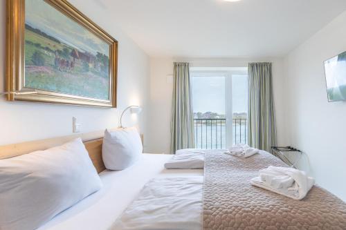 ein Schlafzimmer mit einem Bett mit weißen Laken und einem Fenster in der Unterkunft Ferienwohnung Ferhaaling mit direktem Seeblick in Nordstrand