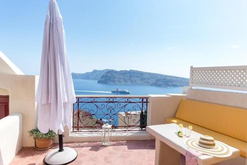 伊亞的住宿－Beautiful Oia Villa - Spectacular Sea Views - Sunset & Caldera Views - Aegean Serenity Villa，阳台配有黄色沙发和雨伞。