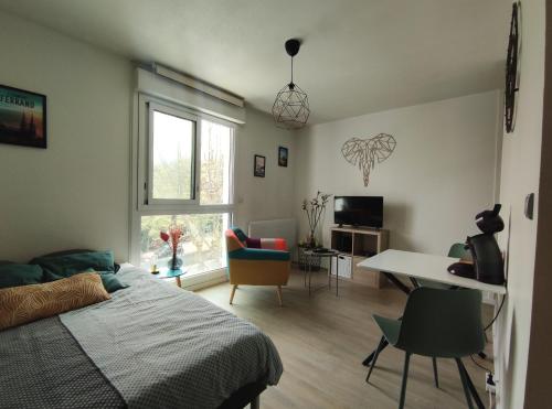 1 dormitorio con 1 cama, mesa y sillas en Hesperie studio, en Chamalières