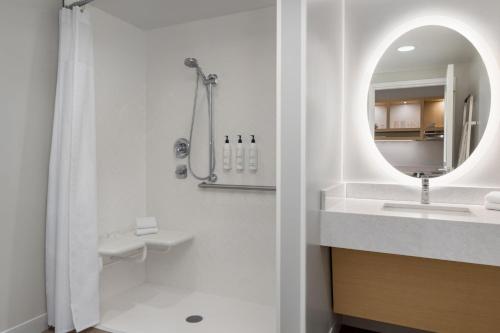 een badkamer met een douche, een wastafel en een spiegel bij TownePlace Suites by Marriott Geneva at SPIRE Academy in Geneva