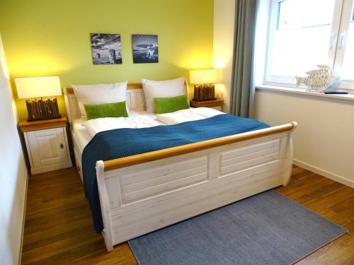 a bedroom with a bed with blue sheets and green pillows at Gode Wind Quartiere 3 in Dahme