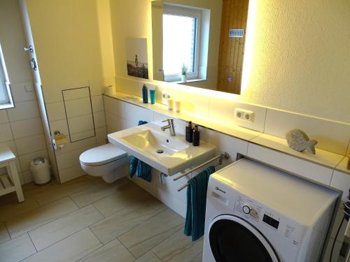 a bathroom with a sink and a washing machine at Gode Wind Quartiere 3 in Dahme