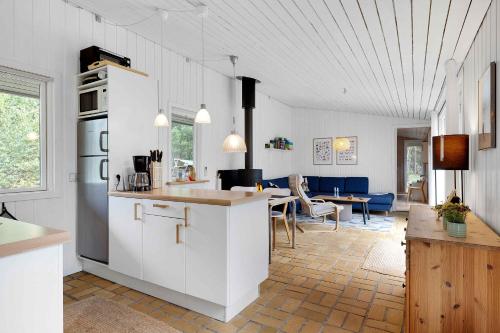 eine Küche mit weißen Schränken und ein Wohnzimmer in der Unterkunft Charming Lovely Forest House in Hadsund
