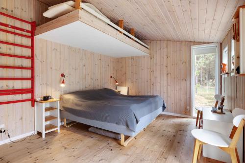 ein Schlafzimmer mit einem Bett in einem Zimmer mit Holzwänden in der Unterkunft Charming Lovely Forest House in Hadsund