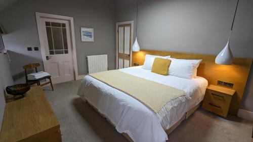 マーサー・ティドビルにあるSpacious Penthouse Apartment in Merthyr Tydfilのベッドルーム1室(白いシーツと黄色い枕の大型ベッド1台付)