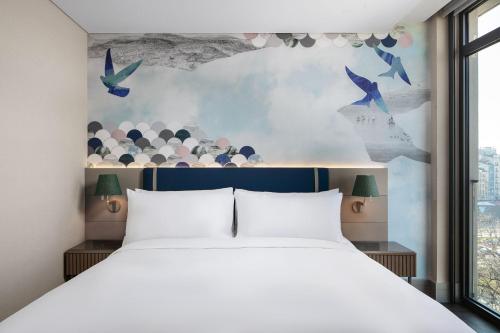 um quarto com uma cama branca e pássaros na parede em Lokalist, Istanbul, a Tribute Portfolio Hotel em Istambul