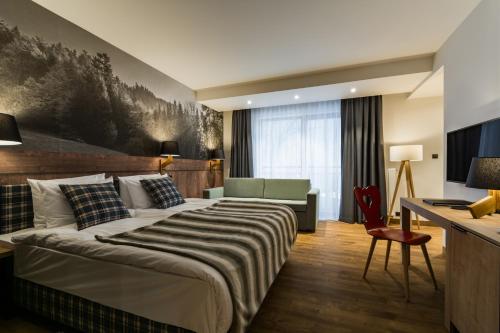 a hotel room with a large bed and a desk at Szczawnica Park Resort & Spa in Szczawnica