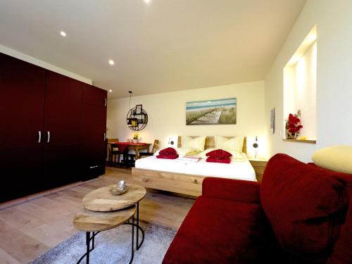 ヴァーネミュンデにあるFerienwohnung Hahnsのベッドルーム1室(ベッド1台、赤いソファ付)