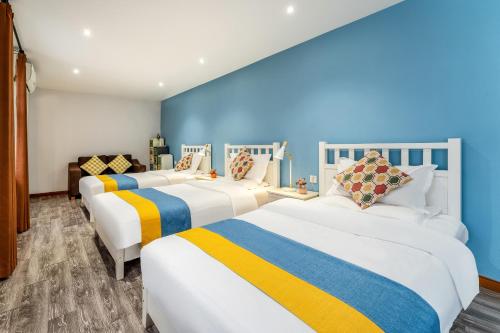 three beds in a room with blue walls at Xi'an See Tang Guesthouse in Xi'an