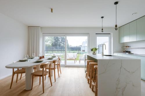 cocina blanca con mesa, sillas y encimera en Huswell - Brand new house "Sable D'or" in Oostduinkerke, en Oostduinkerke