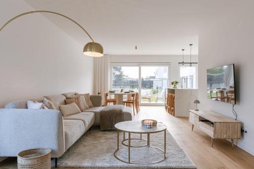 una sala de estar con un sofá y una mesa en Huswell - Brand new house "Sable D'or" in Oostduinkerke, en Oostduinkerke