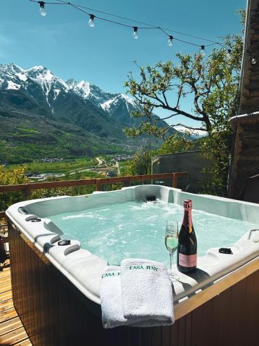 bañera de hidromasaje con botella de vino y copa en Casa Jeny en Fenis