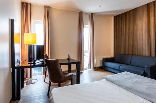 a hotel room with a bed and a desk and a couch at Friendly Cityhotel Oktopus in Siegburg