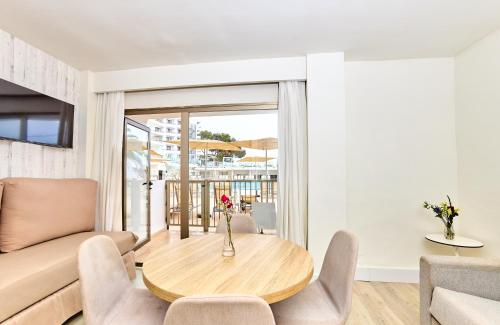 een woonkamer met een tafel en een bank bij Leonardo Royal Hotel Ibiza Santa Eulalia in Es Cana