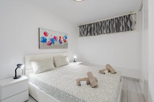a white bedroom with a bed with two towels on it at Un dormitorio en Playa de las Américas in Adeje
