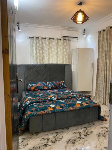 Un dormitorio con una cama gris con un edredón floral. en Graceville apartment, en Lagos