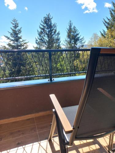 a chair on a balcony with a view of trees at Zlatiborske terase Spa&Wellness in Zlatibor