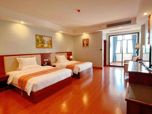 a hotel room with two beds and a desk at Notis International Hotel 诺蒂斯国际酒店 in Phnom Penh