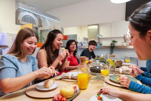 grupa ludzi siedzących przy stole jedzących jedzenie w obiekcie Porto Lounge Hostel & Guesthouse by Host Wise w Porto