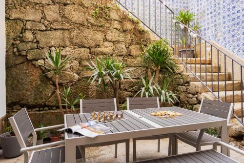 une table et des chaises sur une terrasse avec un mur en pierre dans l'établissement Porto Lounge Hostel & Guesthouse by Host Wise, à Porto