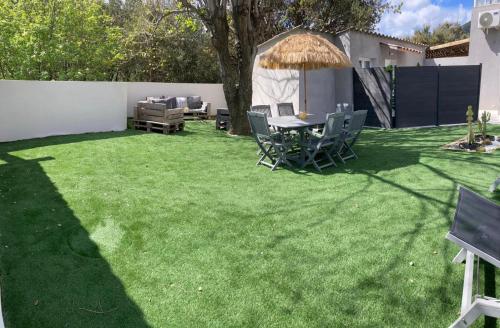 a lawn with a table and chairs on it at Les jardins de funtanone T4 in Vignale