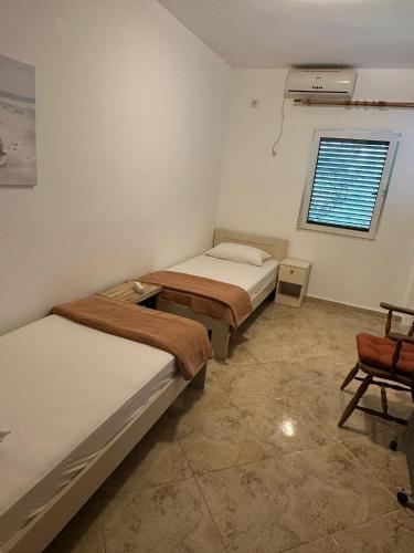a room with two beds and a window and a chair at Apartments Lilly in Ðenovići
