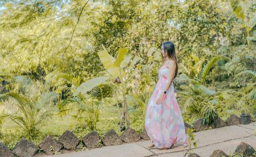 a woman in a pink dress walking down a sidewalk at The Bay Agonda in Agonda