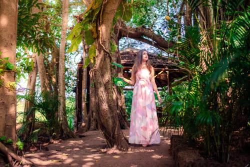 a woman in a dress standing next to a tree at The Bay Agonda in Agonda
