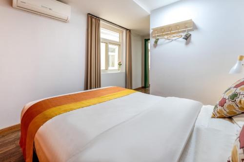 a bedroom with a white bed and a window at Xi'an See Tang Guesthouse in Xi'an